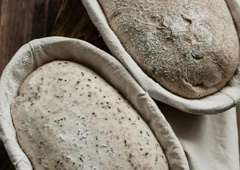 Two loaves proofing in floured cane baskets